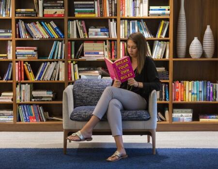 woman sitting in front of stocked bookshelf